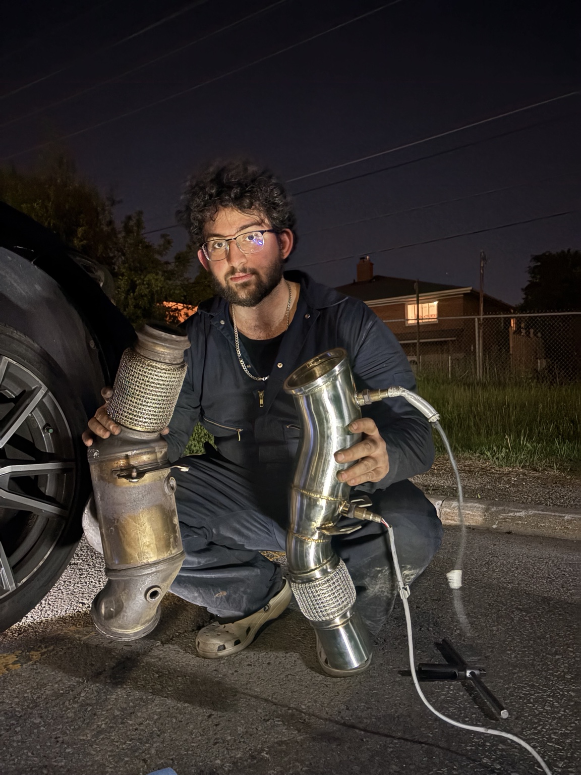 Moe holding BMW downpipe parts after a mobile repair